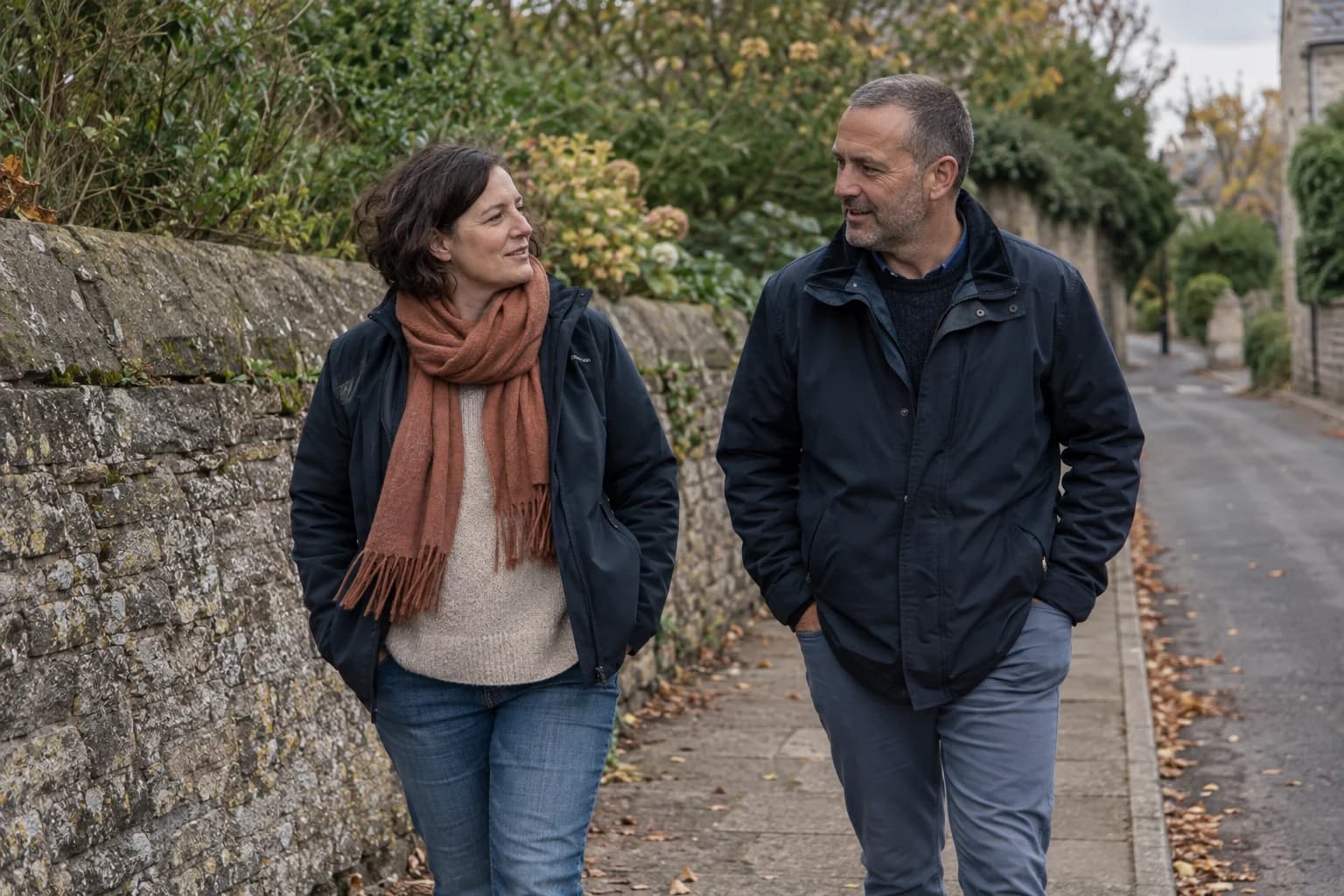 Illustrative lifestyle scene of two adults talking as they walk along a neighbourhood path